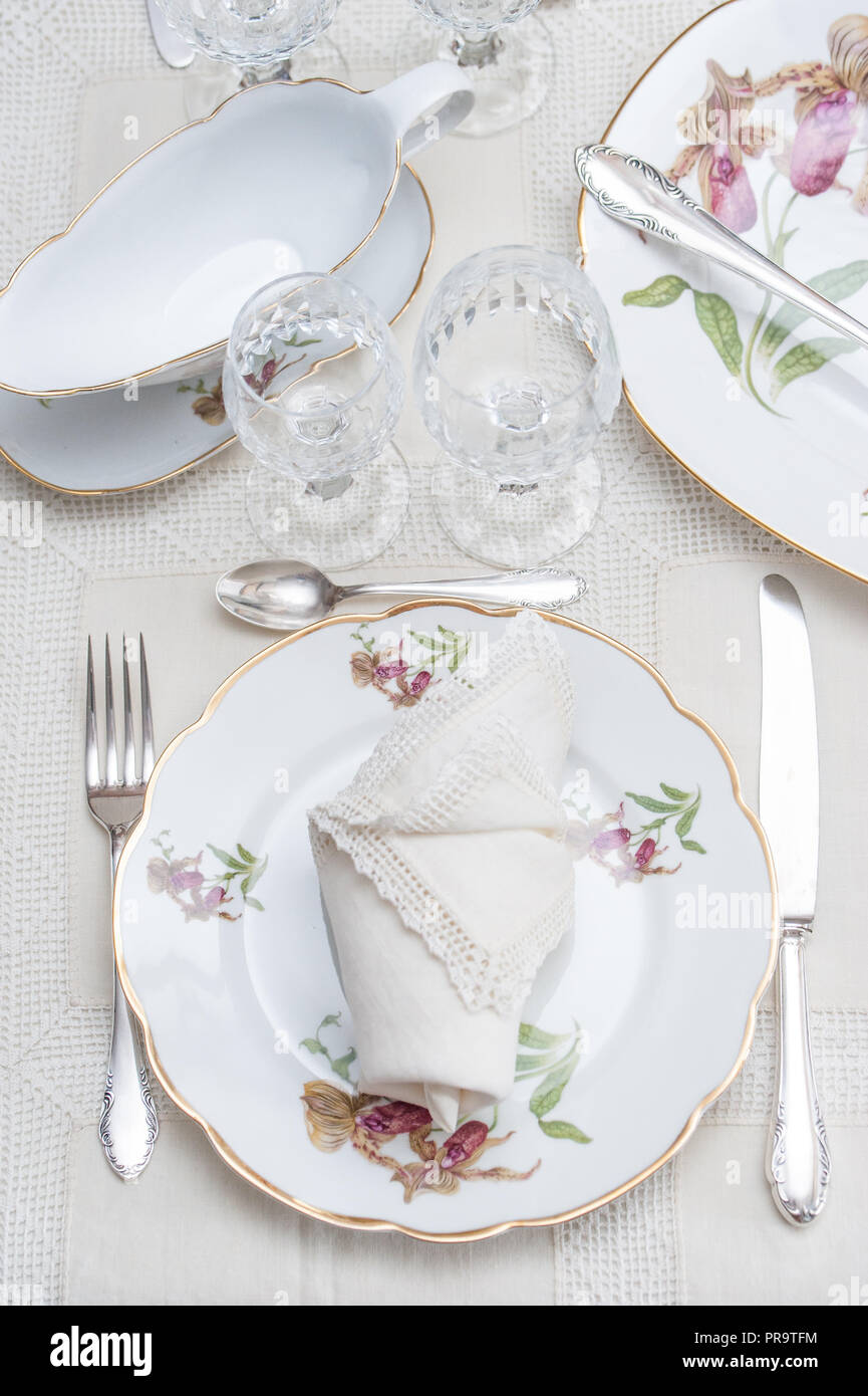Fine dinning: floral pattern white china dinner set arranged on a table  with vintage tablecloth and napikins, crystal glassware. Selective focus  Stock Photo - Alamy