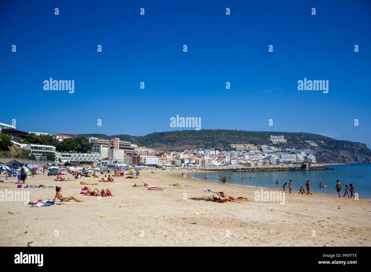 SESIMBRA, PORTUGAL - CIRCA SEPTEMBER, 2018: People on the beach with village on the background Stock Photo