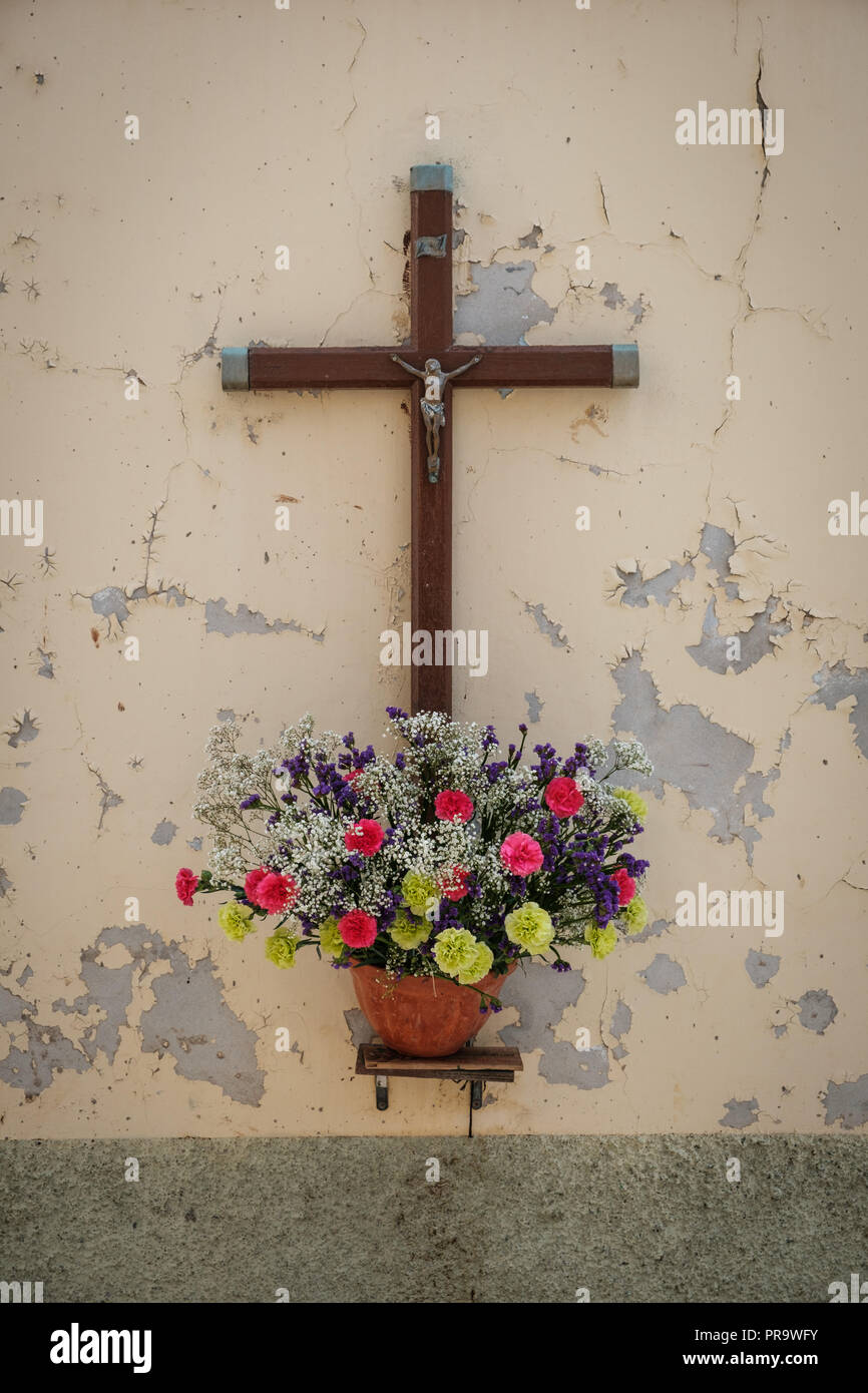 crucifix on wall with flowers - Jesus sculpture on cross on vintage background - Stock Photo