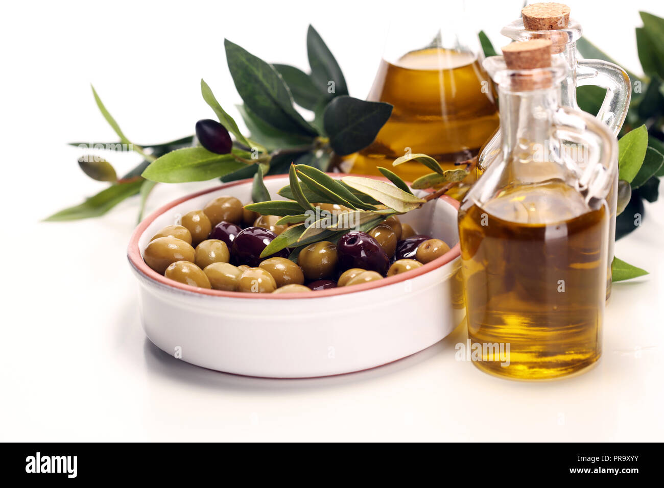 Bottle virgin olive oil and oil in a bowl with some olives Stock Photo ...