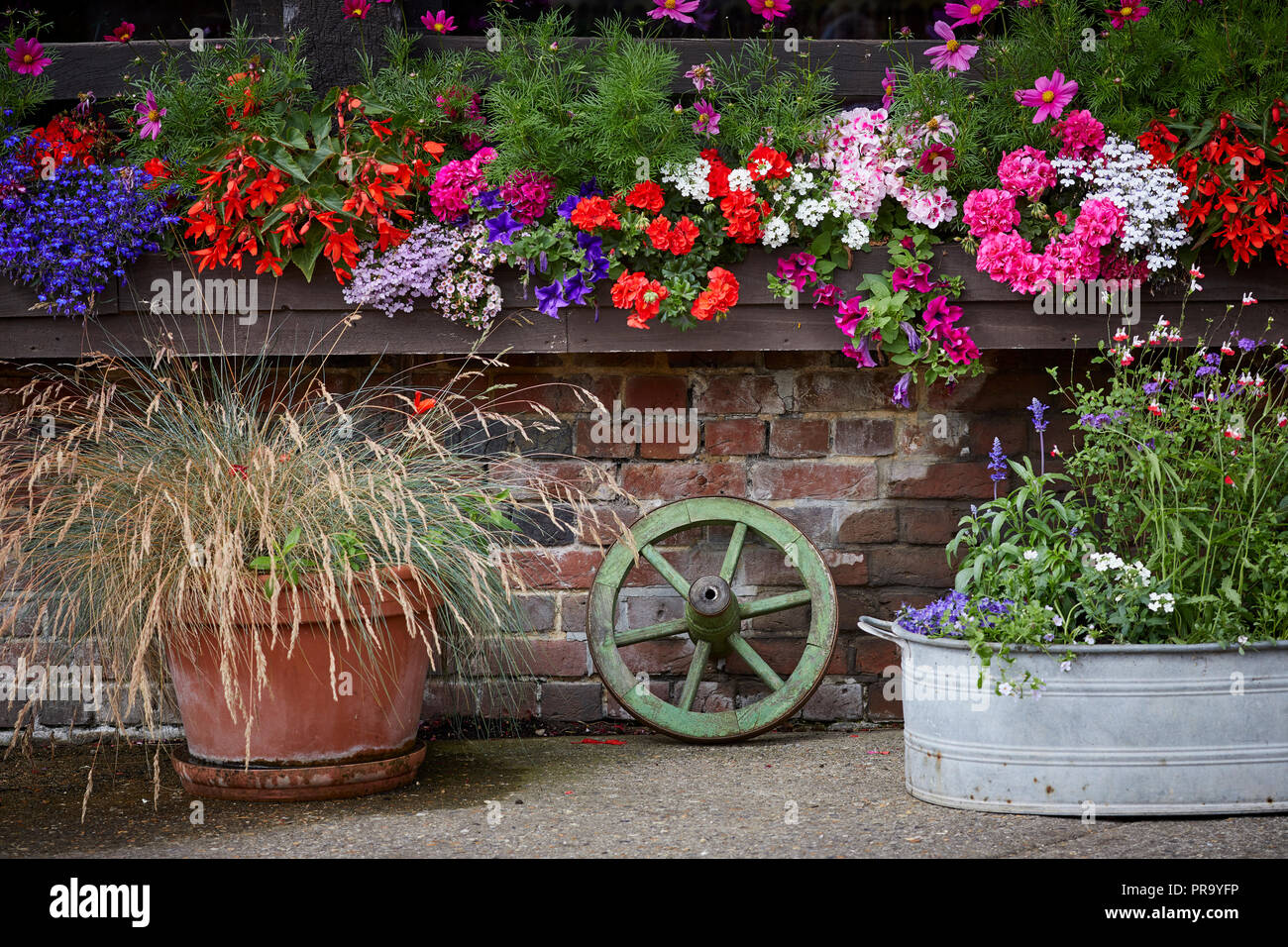 Lillibrooke Manor barns a flower planters and a small cart wheel decorate the gardens Stock Photo
