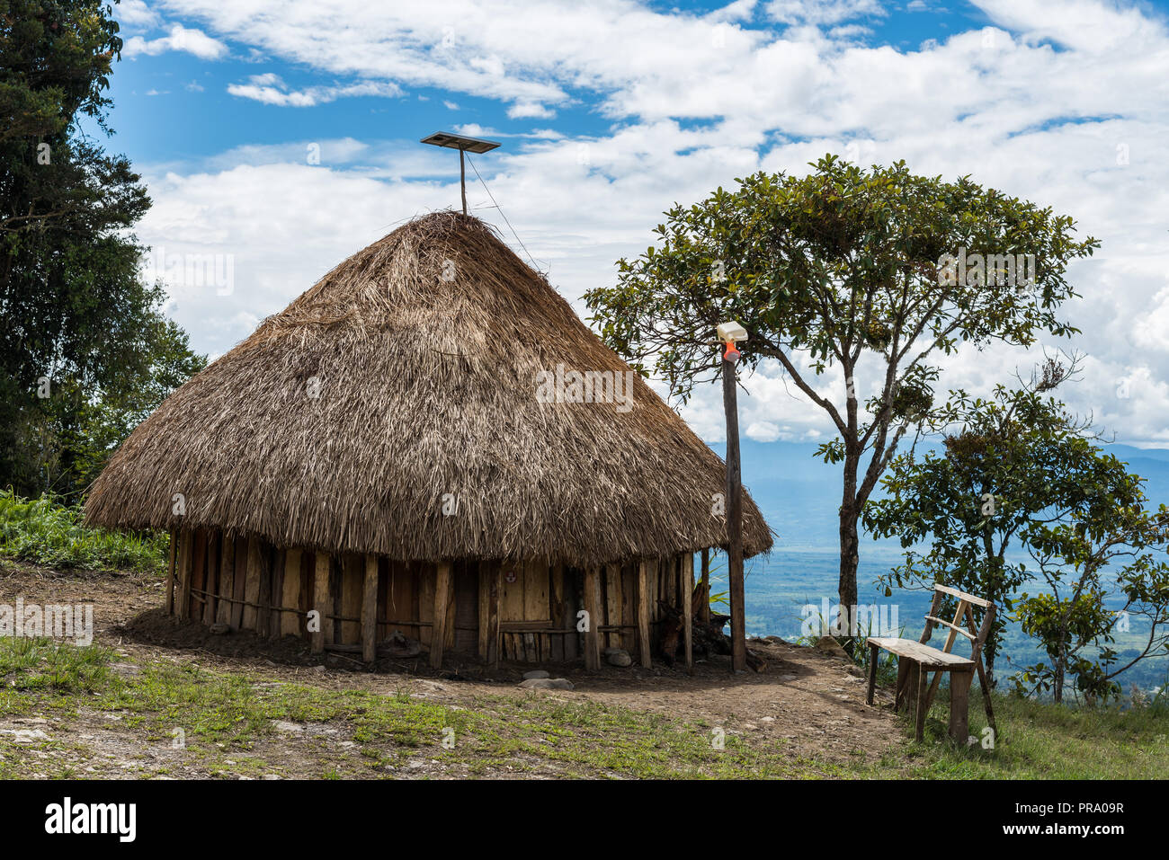 Solar panel and electric light becomes part of grass-topped hut of native Dani people. Wamena, Papua, Indonesia. Stock Photo