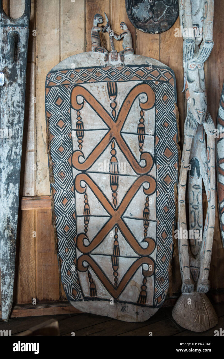 A colorfully painted war shield and other native artifacts. Wamena, Papua, Indonesia. Stock Photo