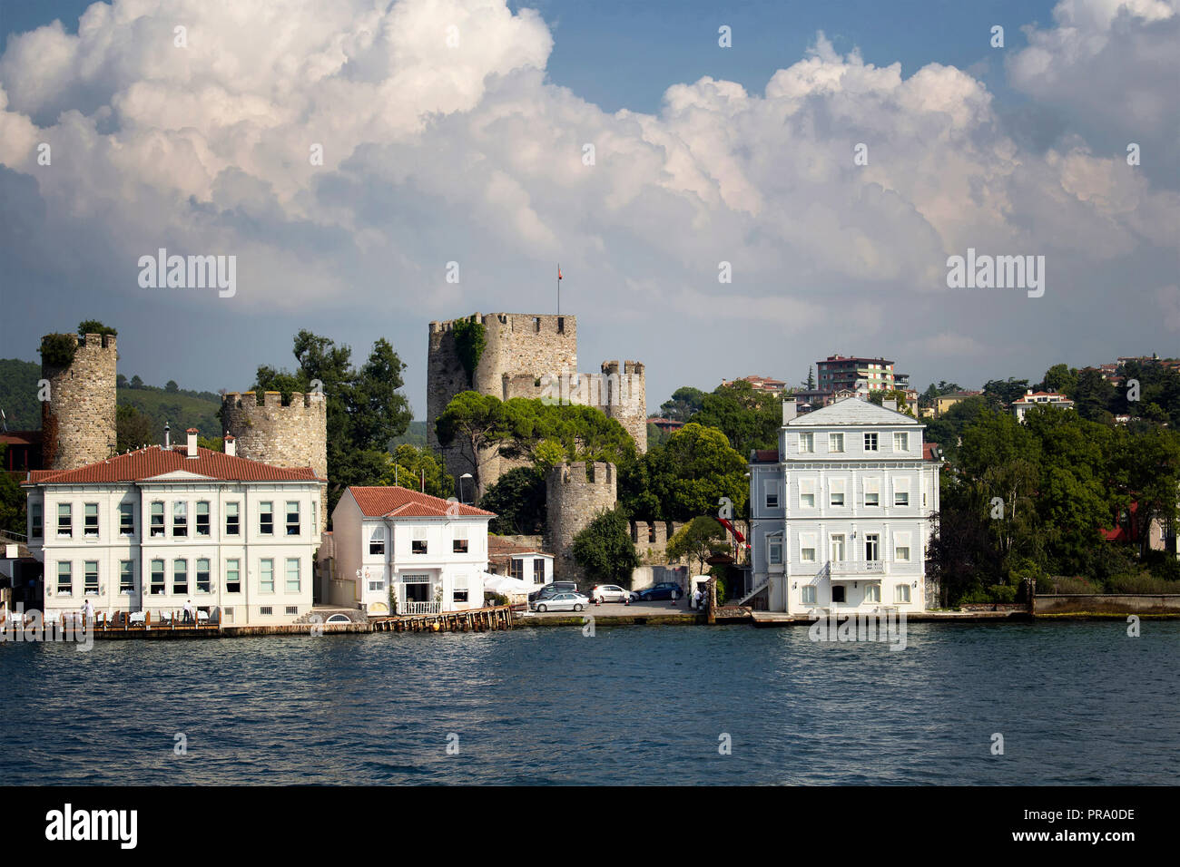View of historical, old Turkish / Ottoman houses and a castle by Bosphorus on Asian side of Istanbul. It is a sunny / cloudy summer day. Stock Photo