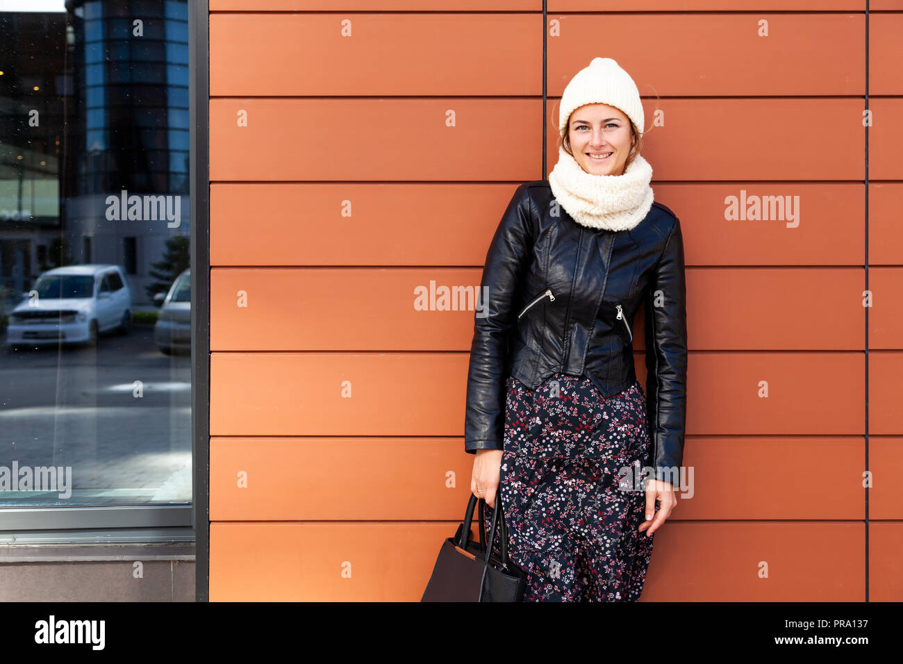 Portrait of a beautiful young model in pink knitted hat, leather jacket ...
