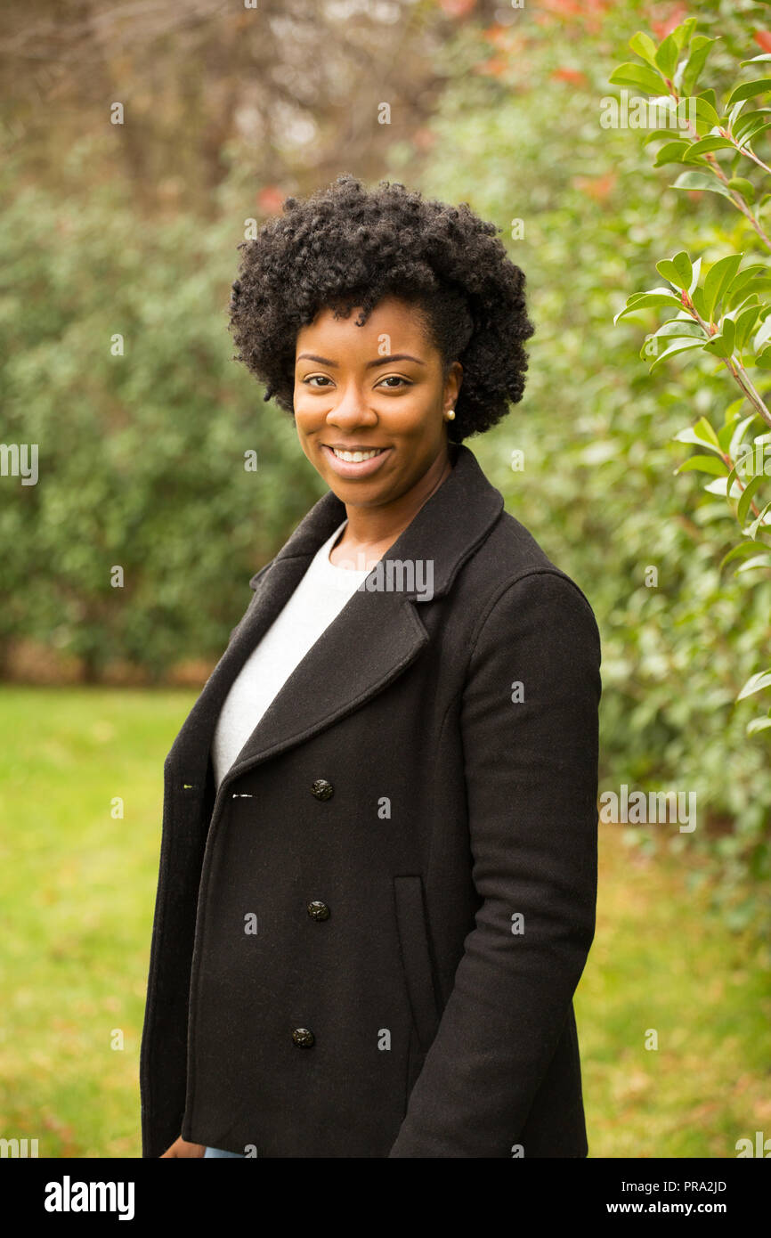 African American woman with curly hair smiling outside Stock Photo - Alamy