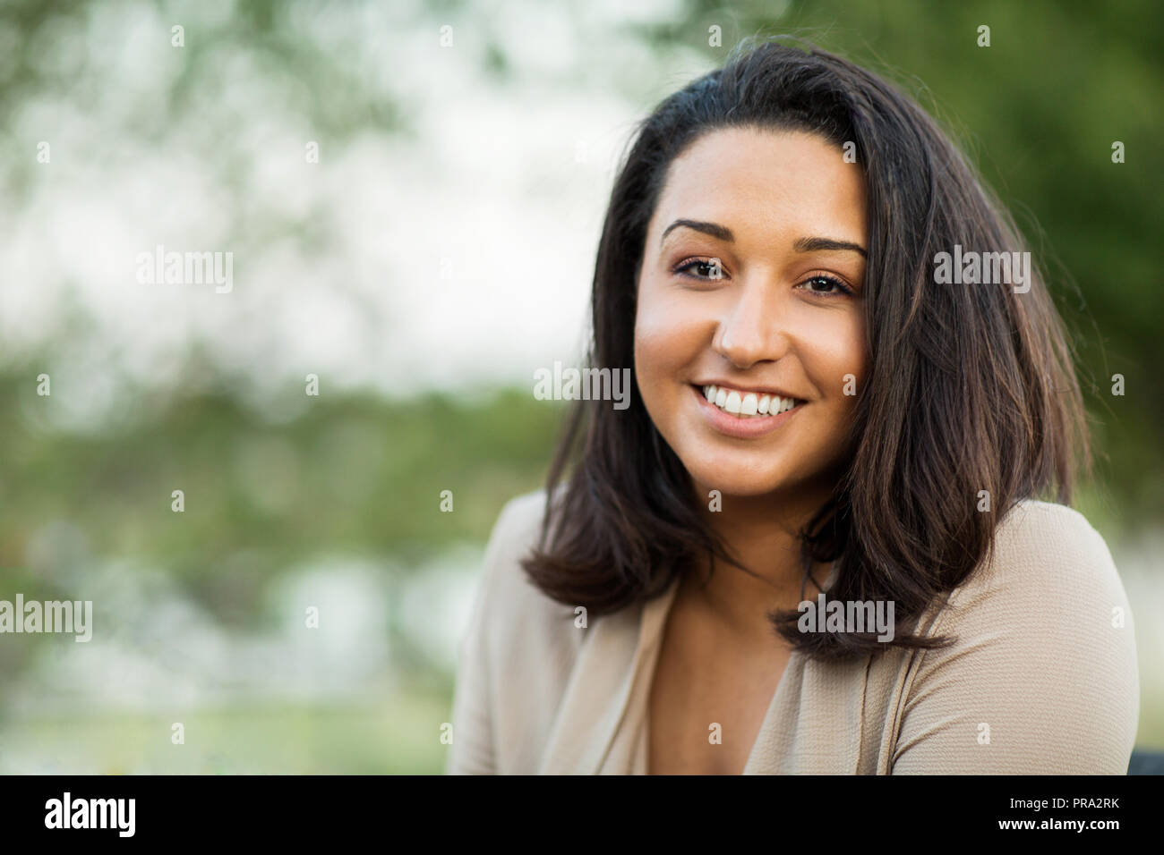 Young confident happy Hispanic woman smiling outside. Stock Photo