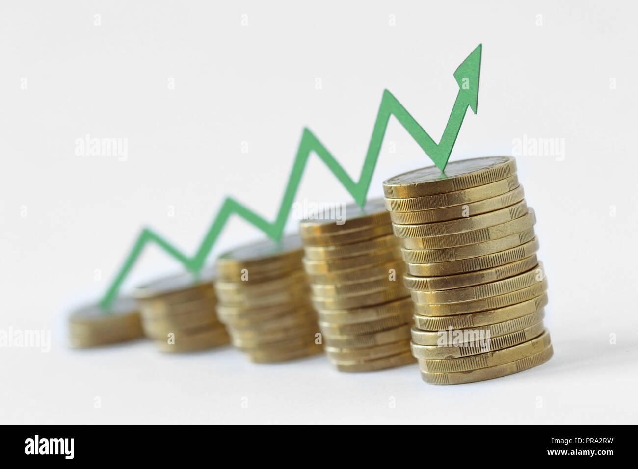 Piles of coins with green raising arrow - Money growth concept Stock Photo