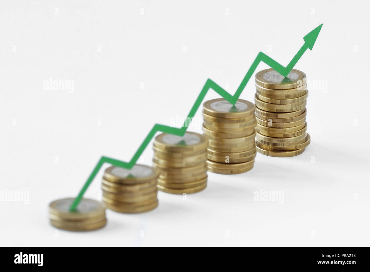 Piles of coins with green raising arrow - Money growth concept Stock Photo