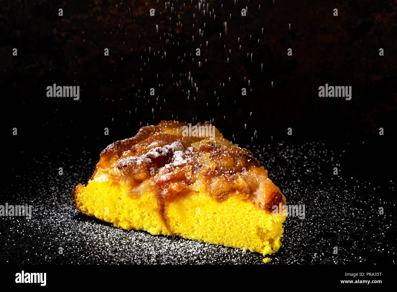 One slice of an apple cake with powder sugar on a dark background Stock Photo