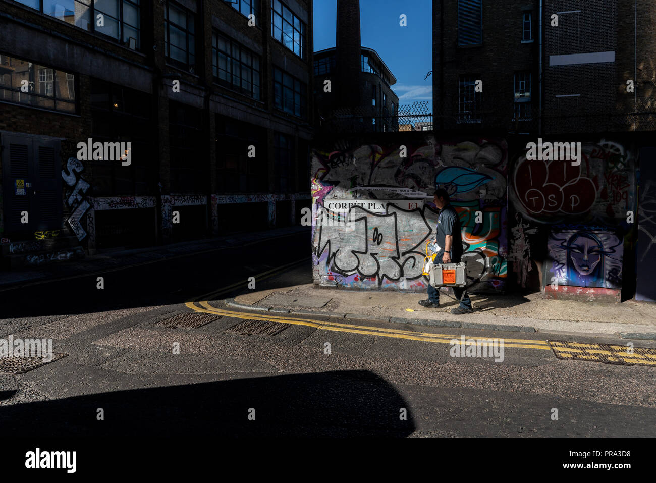 A man makes his way along a Shoreditch back street in low sun on a summers day, London UK Stock Photo