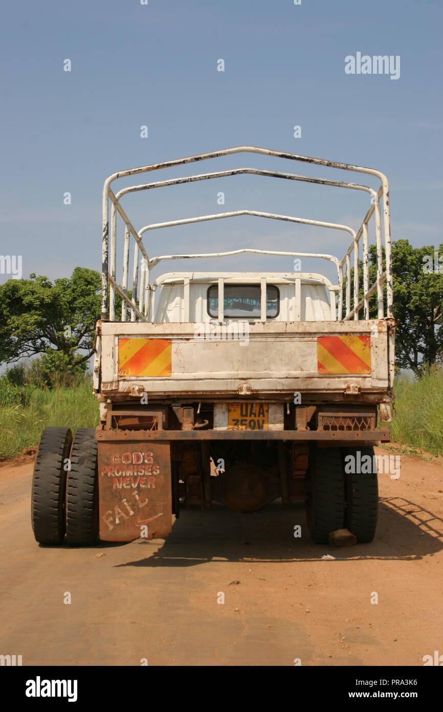 A truck awaits repairs to a broken axle in Northern Uganda. On the mudguard are written the words 'God's Promises Never Fail'. Stock Photo