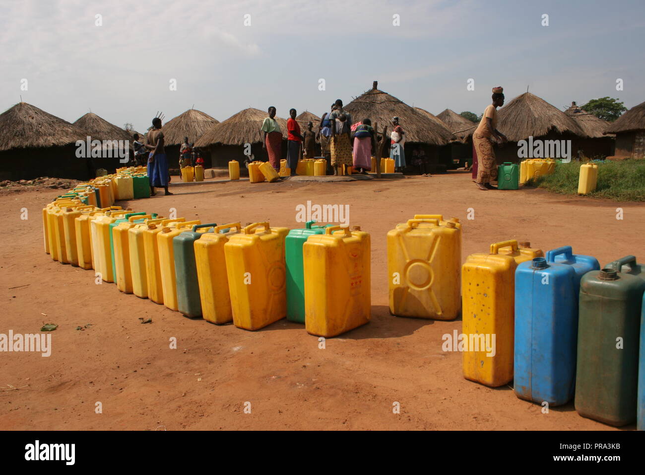 A long line of jerrycans wait to be filled at a single water borehole in Atiak internally displaced people's (IDP) camp, Northern Uganda. Stock Photo