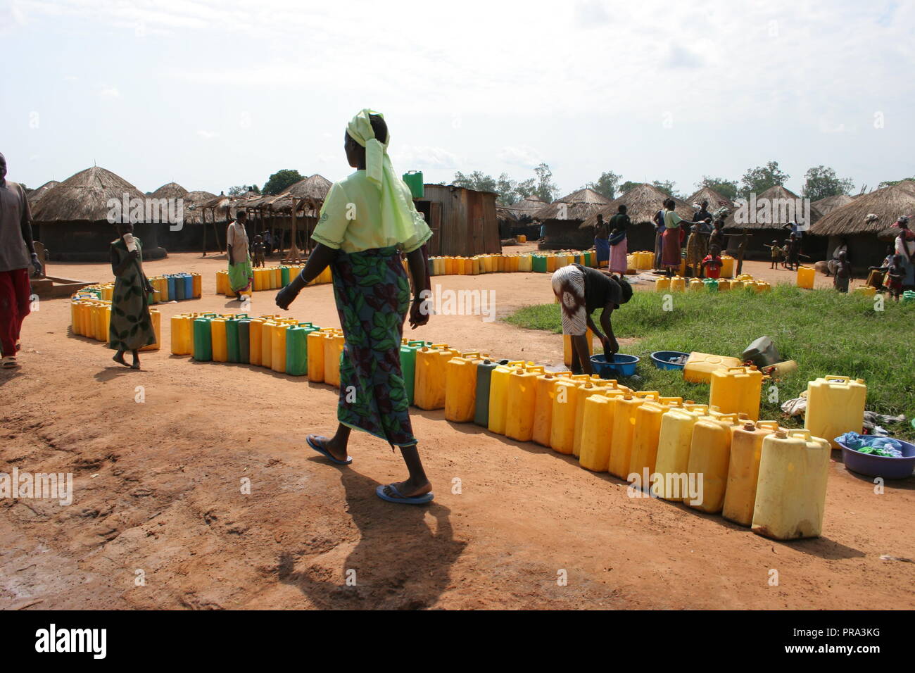 A long line of jerrycans wait to be filled at a single water borehole in Atiak internally displaced people's (IDP) camp, Northern Uganda. Stock Photo