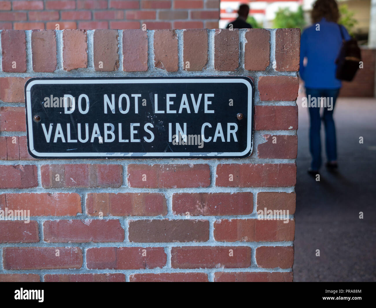 Some people walking away from do not leave valuables in car sign  Stock Photo