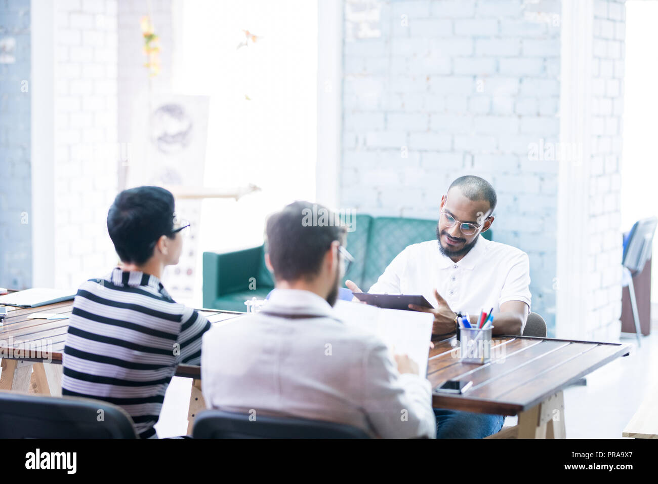 Mixed race manager analyzing statistics presented by staff Stock Photo