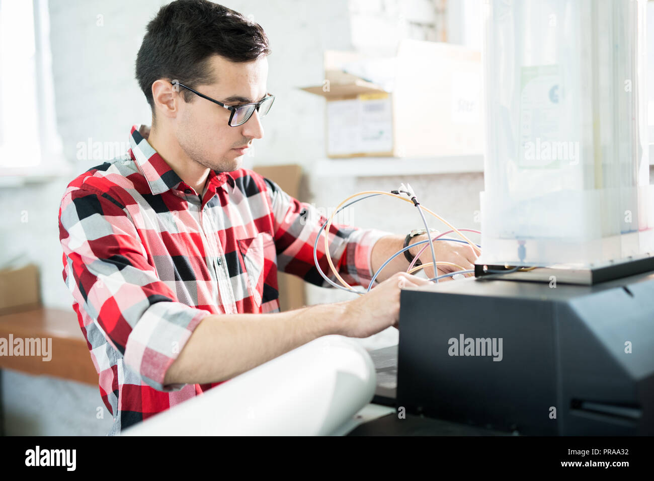 Busy engineer repairing printer in office of printing company Stock