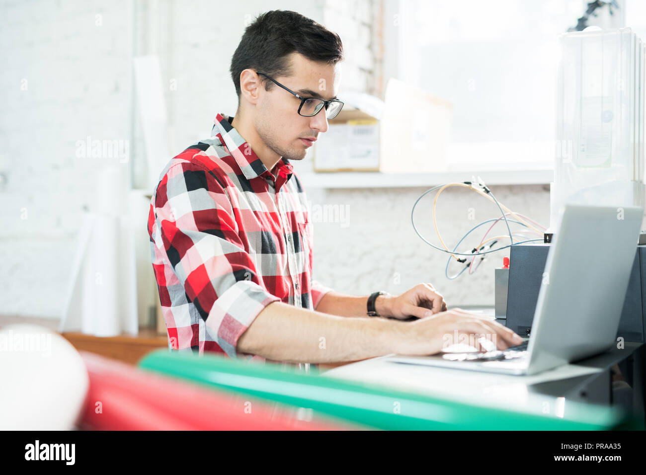 Serious technician testing printer on laptop Stock Photo