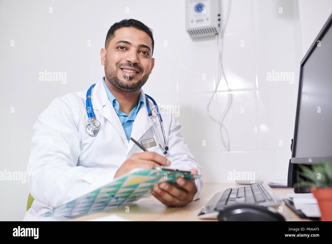 Middle-Eastern Doctor Posing at Desk Stock Photo