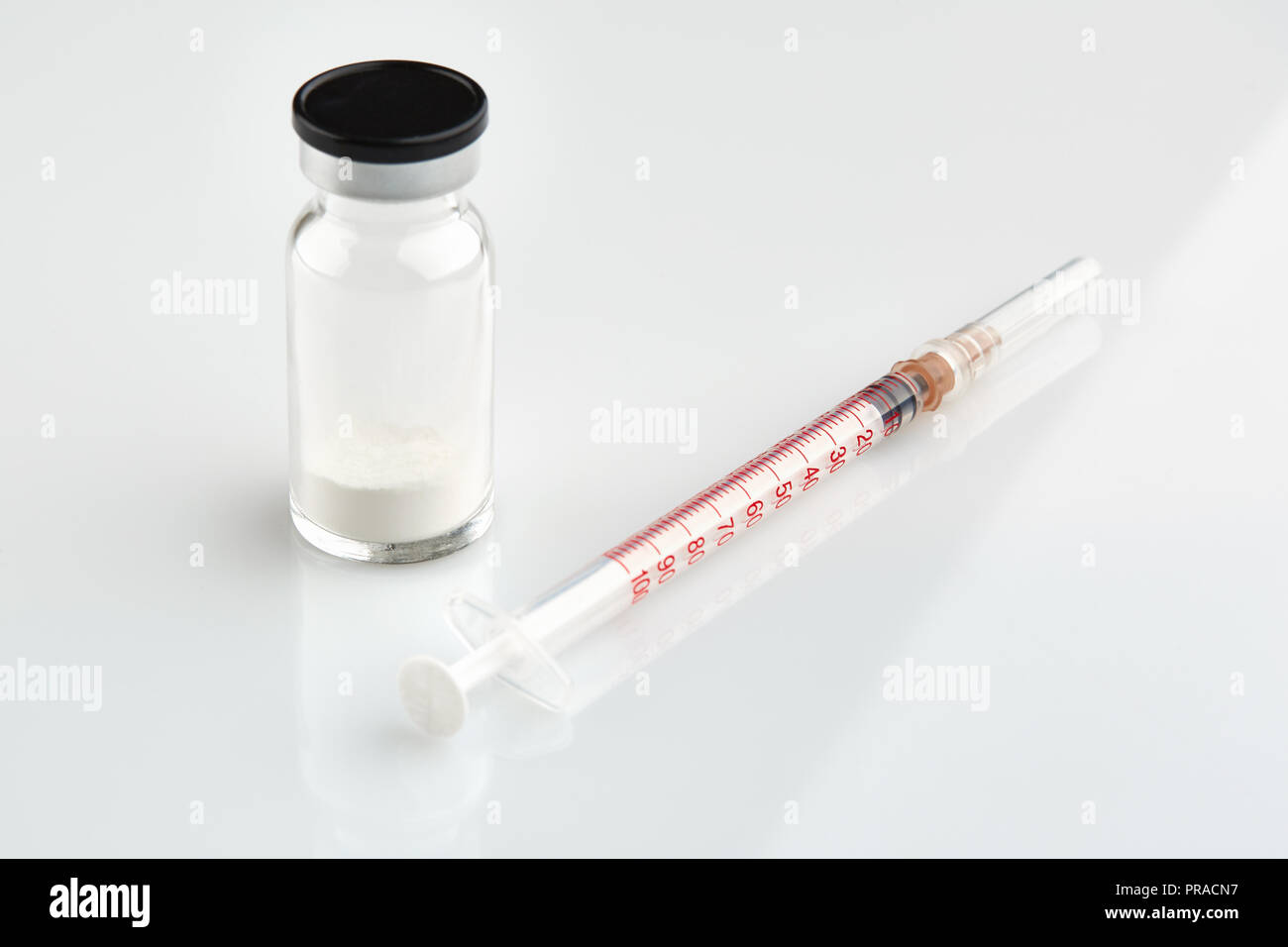 Small sealed bottle with medicine and syringe on white background. Stock Photo