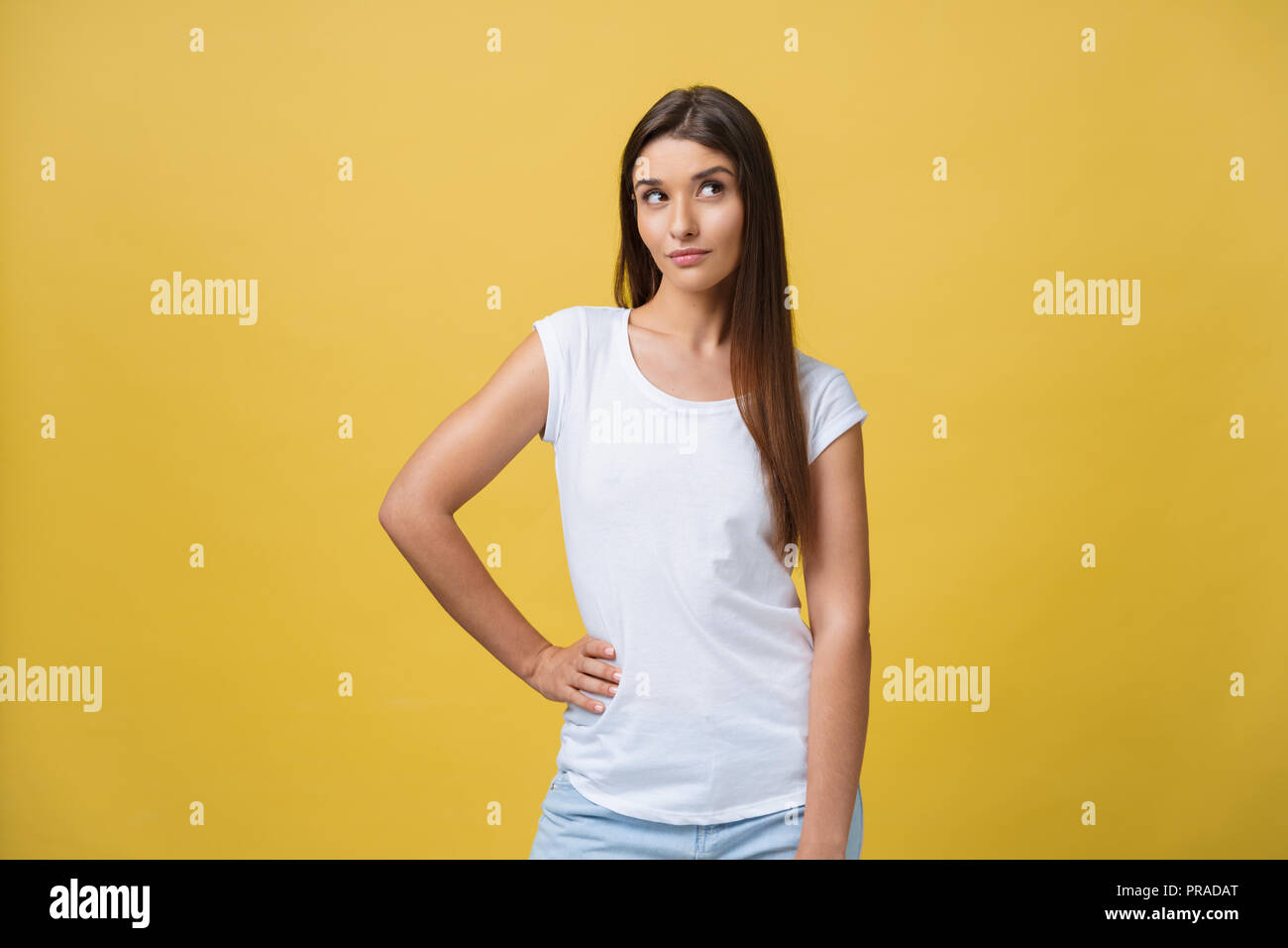 portrait of the beautiful young woman thinking on the yellow background ...