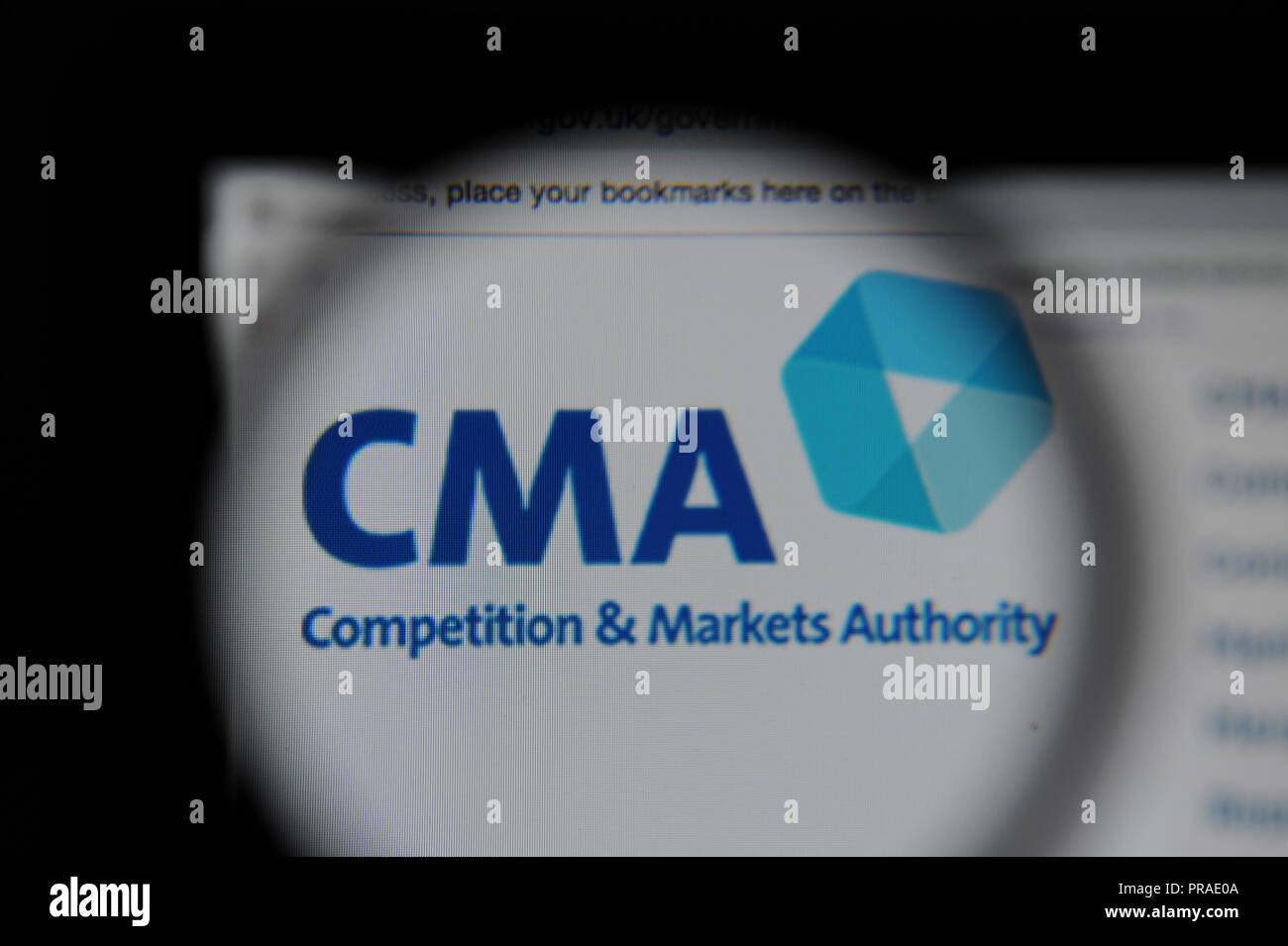 The Competition and Markets Authority (CMA) website seen through a magnifying glass Stock Photo