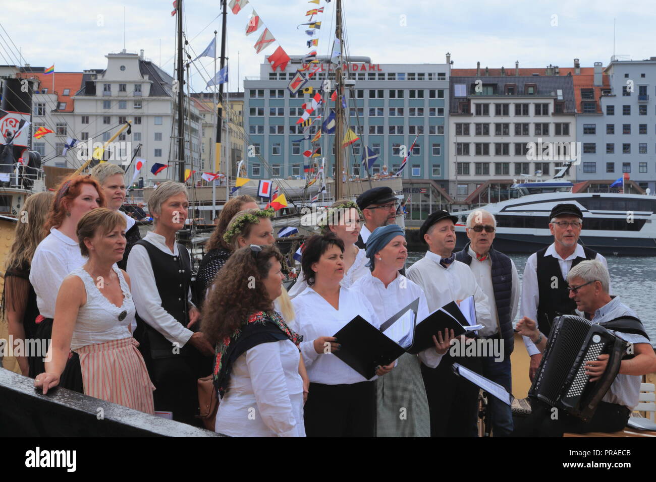 A choir sings traditional Norwegian songs on the deck of a boat in Bergen harbour, Norway, during the Market Day (Torgdagen). Stock Photo
