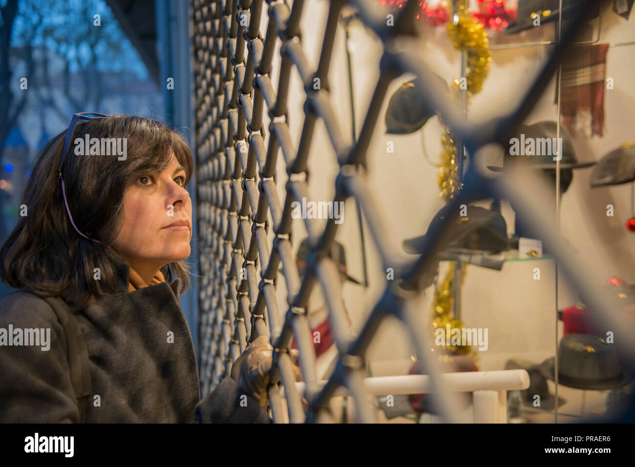 Woman Looking at Window Store with Metal Grate in France. Stock Photo