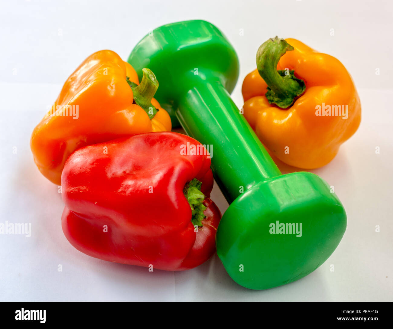 The concept of fitness. multicolored pepper near Green dumbbell Stock Photo