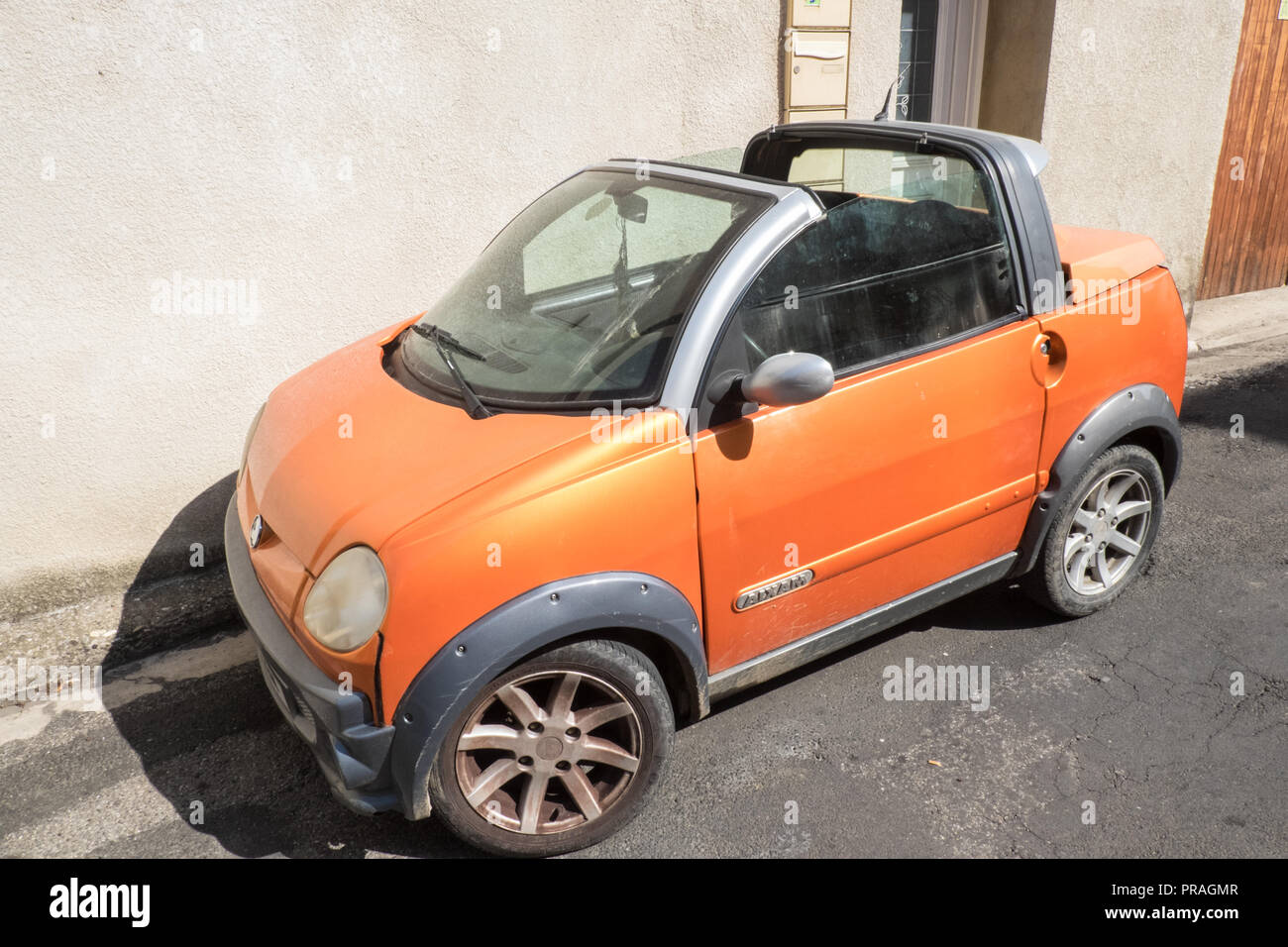 Orange,tiny,Aixam,French,compact,car,parked,on,street,Esperaza,Aude,region,South of France,France,Europe,European,model, Stock Photo