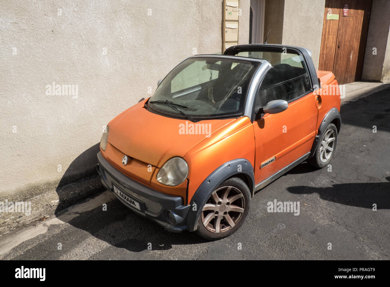 Orange,tiny,Aixam,French,compact,car,parked,on,street,Esperaza,Aude,region,South of France,France,Europe,European,model, Stock Photo