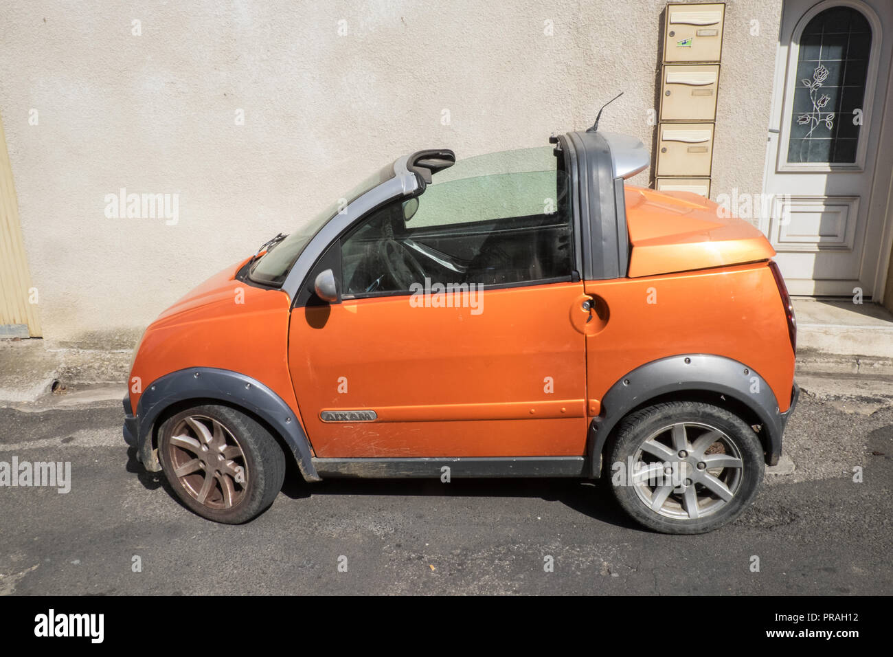 Orange,tiny,Aixam,French,compact,car,parked,on,street,Esperaza,Aude,region,South of France,France,Europe,European,model, Stock Photo