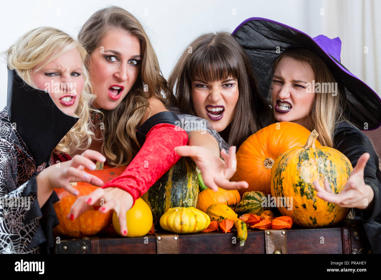Four beautiful women acting as witches joining their malicious forces Stock Photo