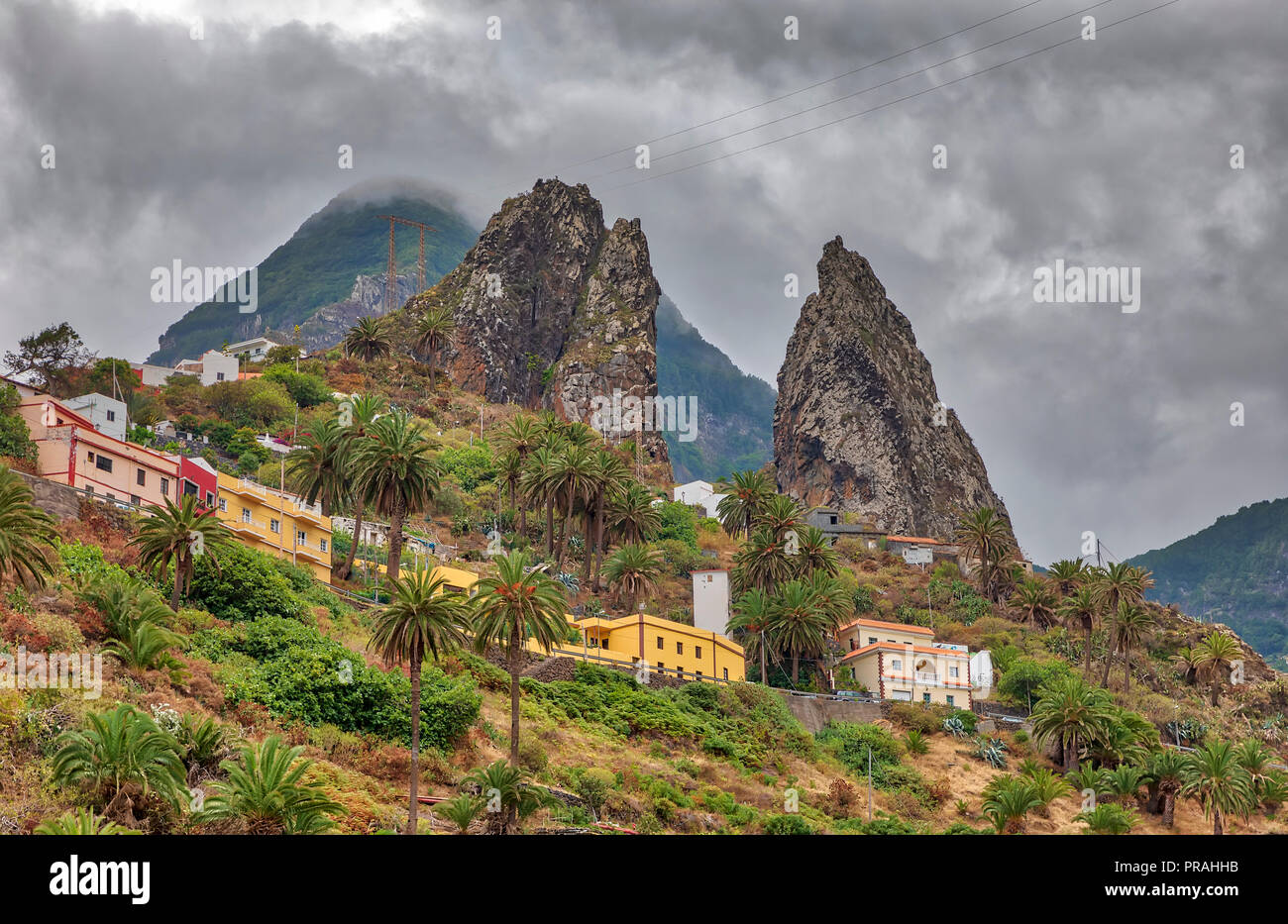 LA GOMERA, SPAIN - AUGUST 18: (EDITORS NOTE: Image is a digital [High Dynamic Range, HDR] composite.) Two huge rocks tower over the village at Hemigua on August 18, 2018 in La Gomera, Spain. The mountains of the island are often covered by clouds in summer too. Stock Photo