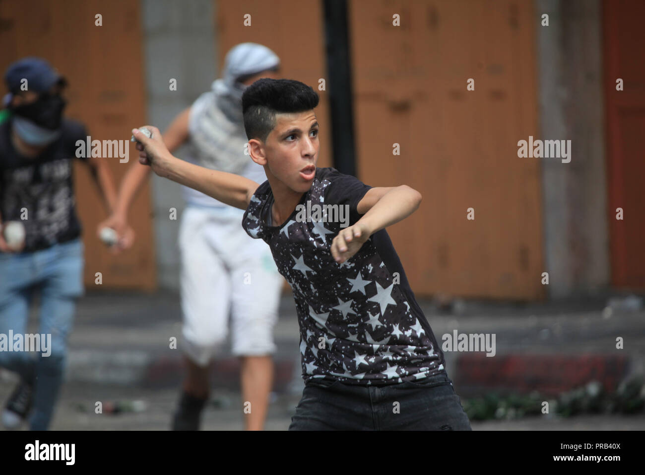 Hebron, West Bank City of Hebron. 1st Oct, 2018. A Palestinian boy hurls stones at Israeli soldiers during clashes after a protest against the recently passed Jewish nation state law, in the West Bank City of Hebron, on Oct. 1, 2018. Credit: Mamoun Wazwaz/Xinhua/Alamy Live News Stock Photo
