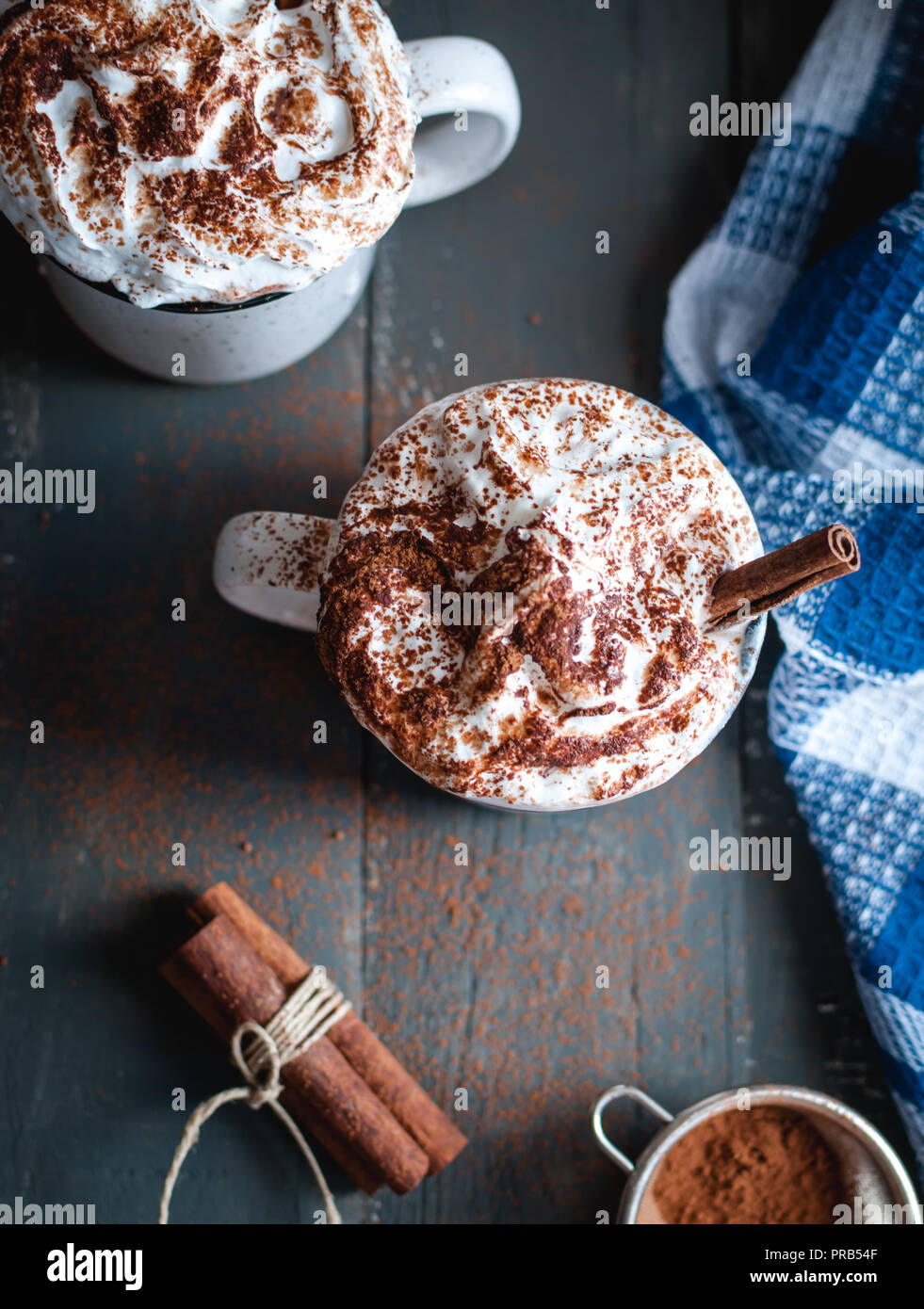 Hot cocoa with whipped cream and cinnamon stick on dark background, top view Stock Photo
