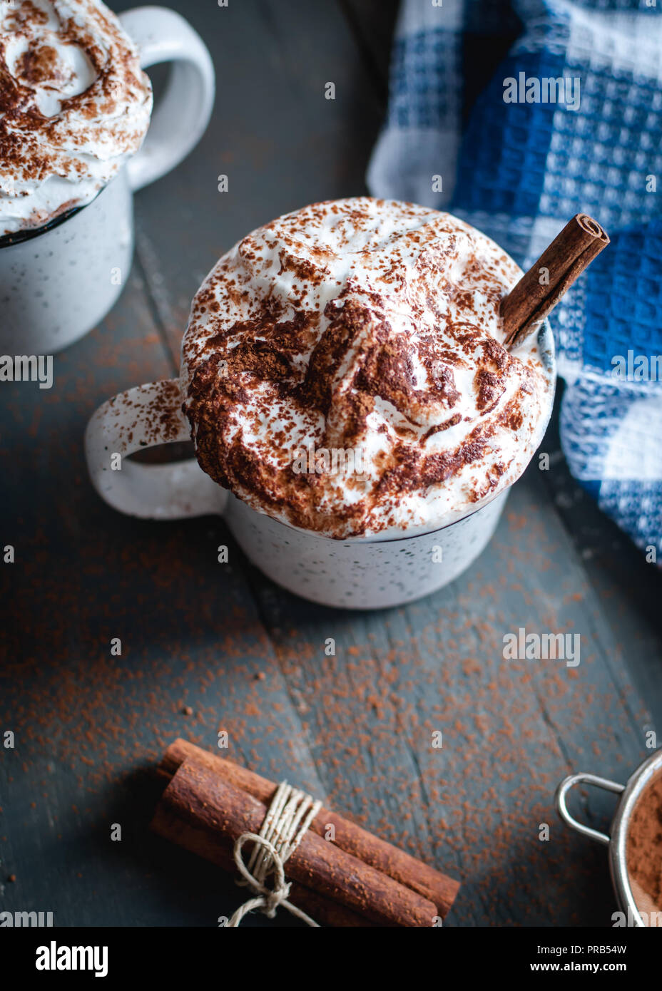Hot cocoa with whipped cream and cinnamon stick on dark background, top view Stock Photo