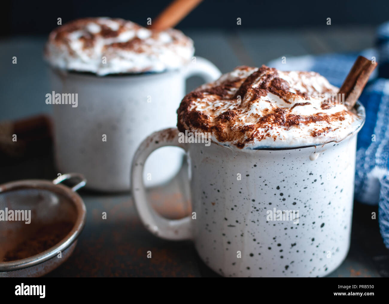 Close-up of hot cocoa with whipped cream and cinnamon stick on dark background Stock Photo