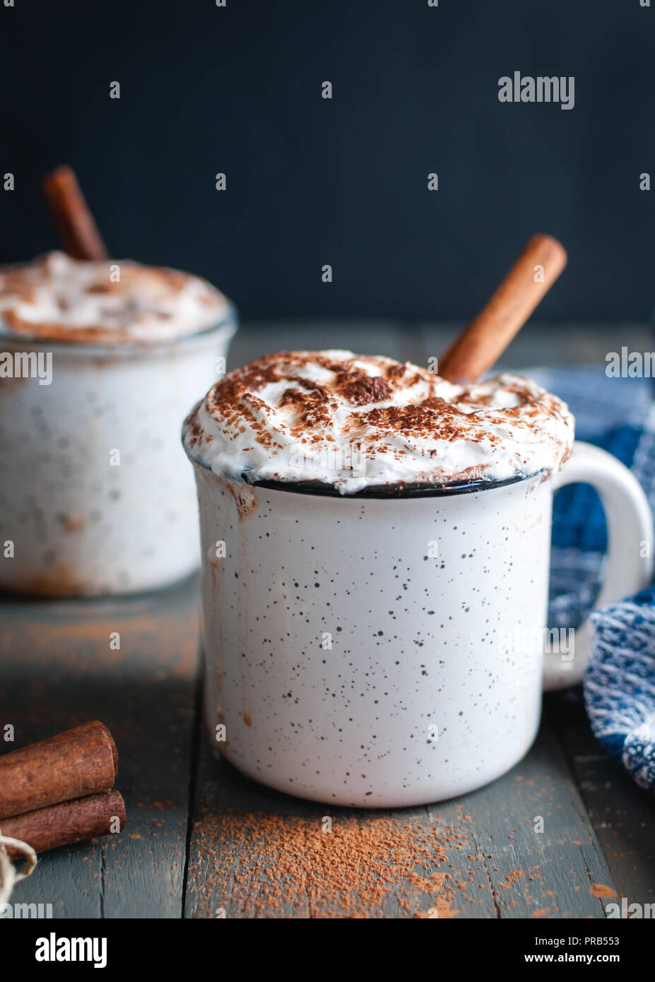 Close-up of hot cocoa with whipped cream and cinnamon stick on dark background Stock Photo