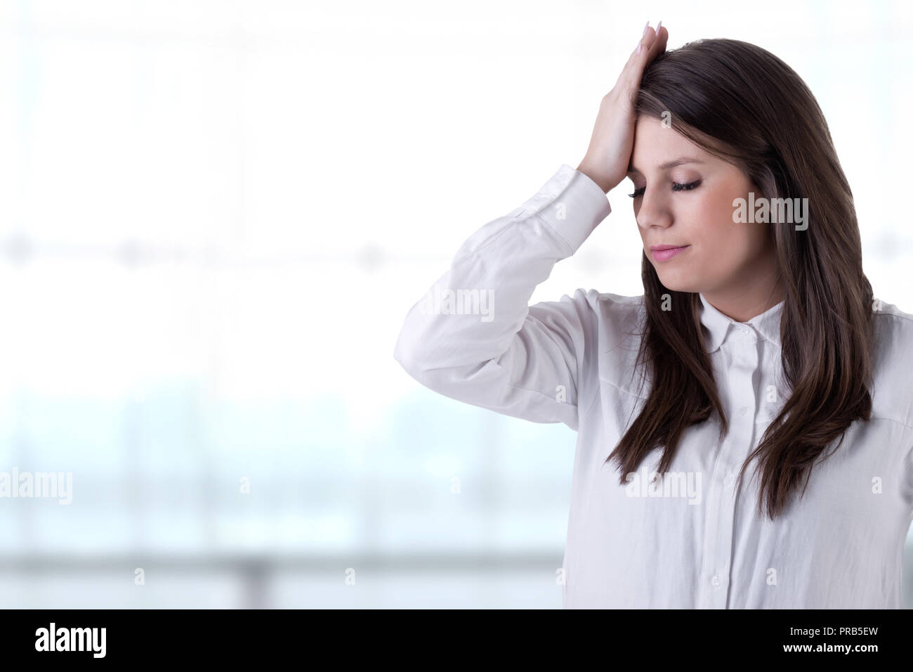 Girl holding her hand to her forehead in a sign of trouble in the office Stock Photo