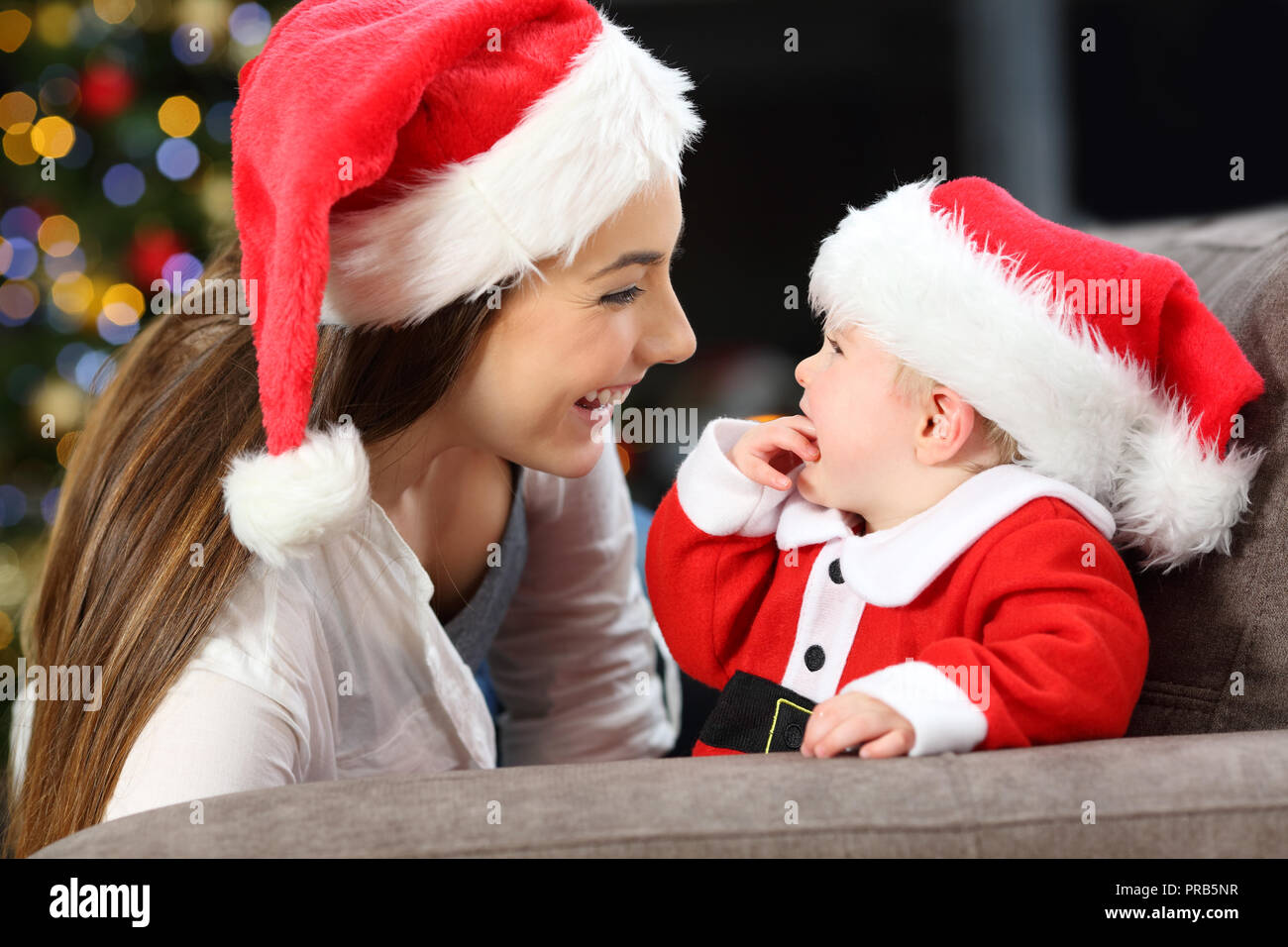 Happy mother and baby looking each other in christmas lying on a couch in the living room at home Stock Photo