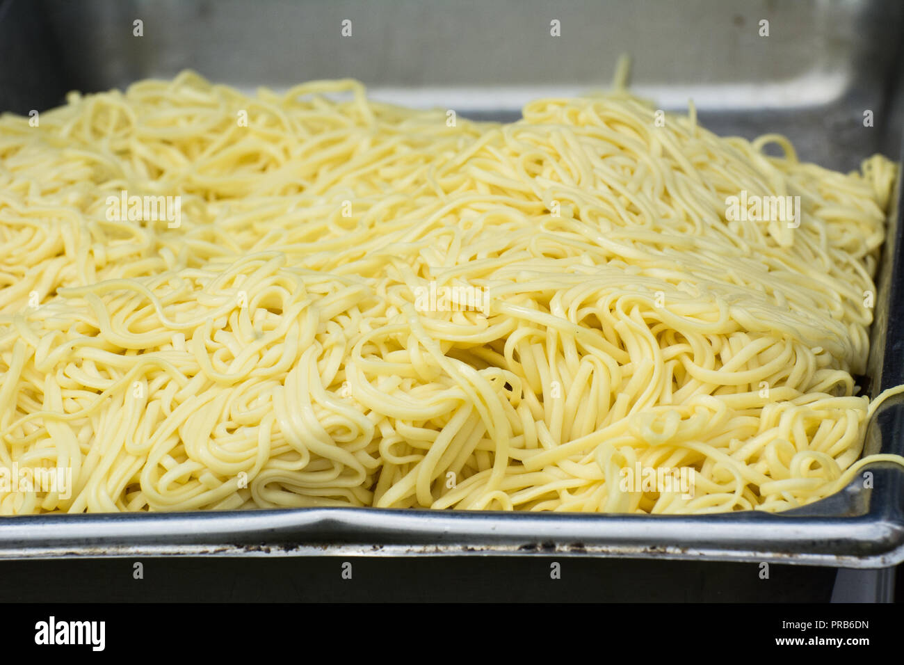 A large tray of spaghetti noodles with no sauce on them. Stock Photo