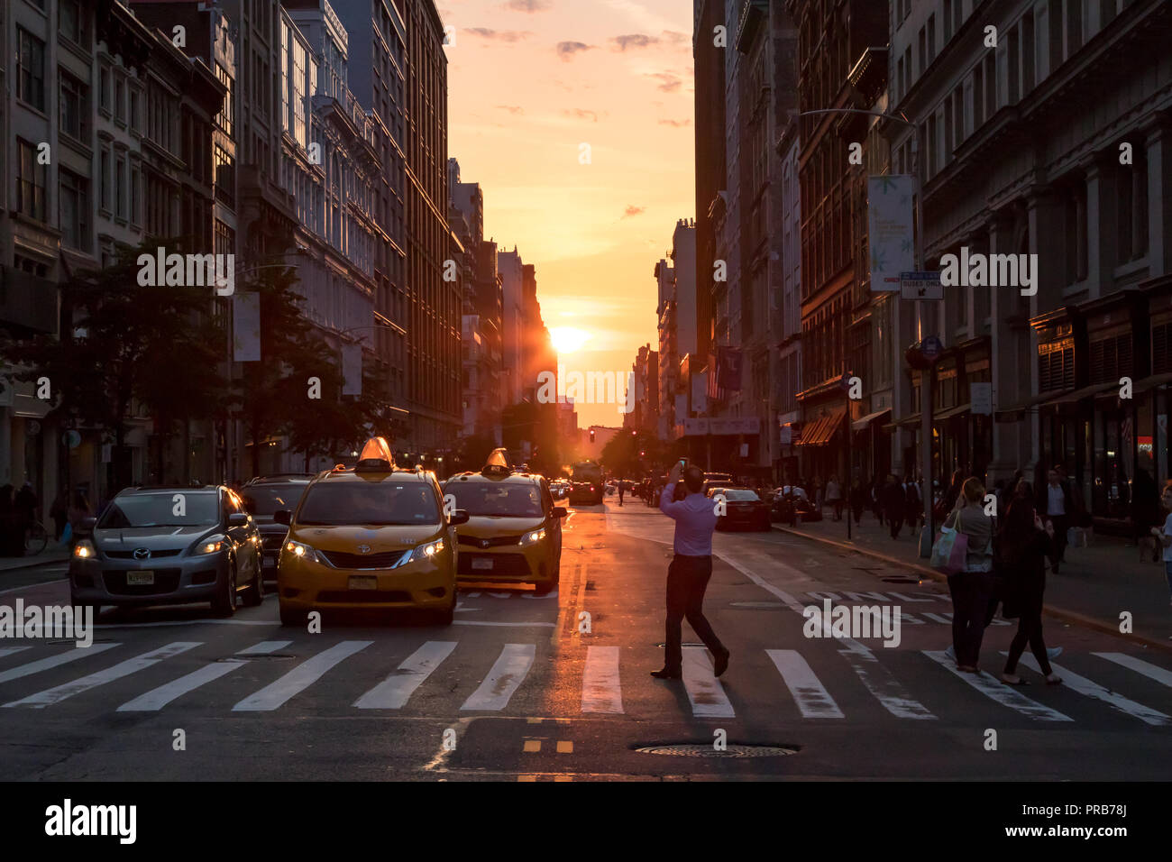 NEW YORK CITY, CIRCA 2018: Man stands in the middle of the intersection on 23rd Street in taking a photo of the evening sunset in Manhattan, New York  Stock Photo