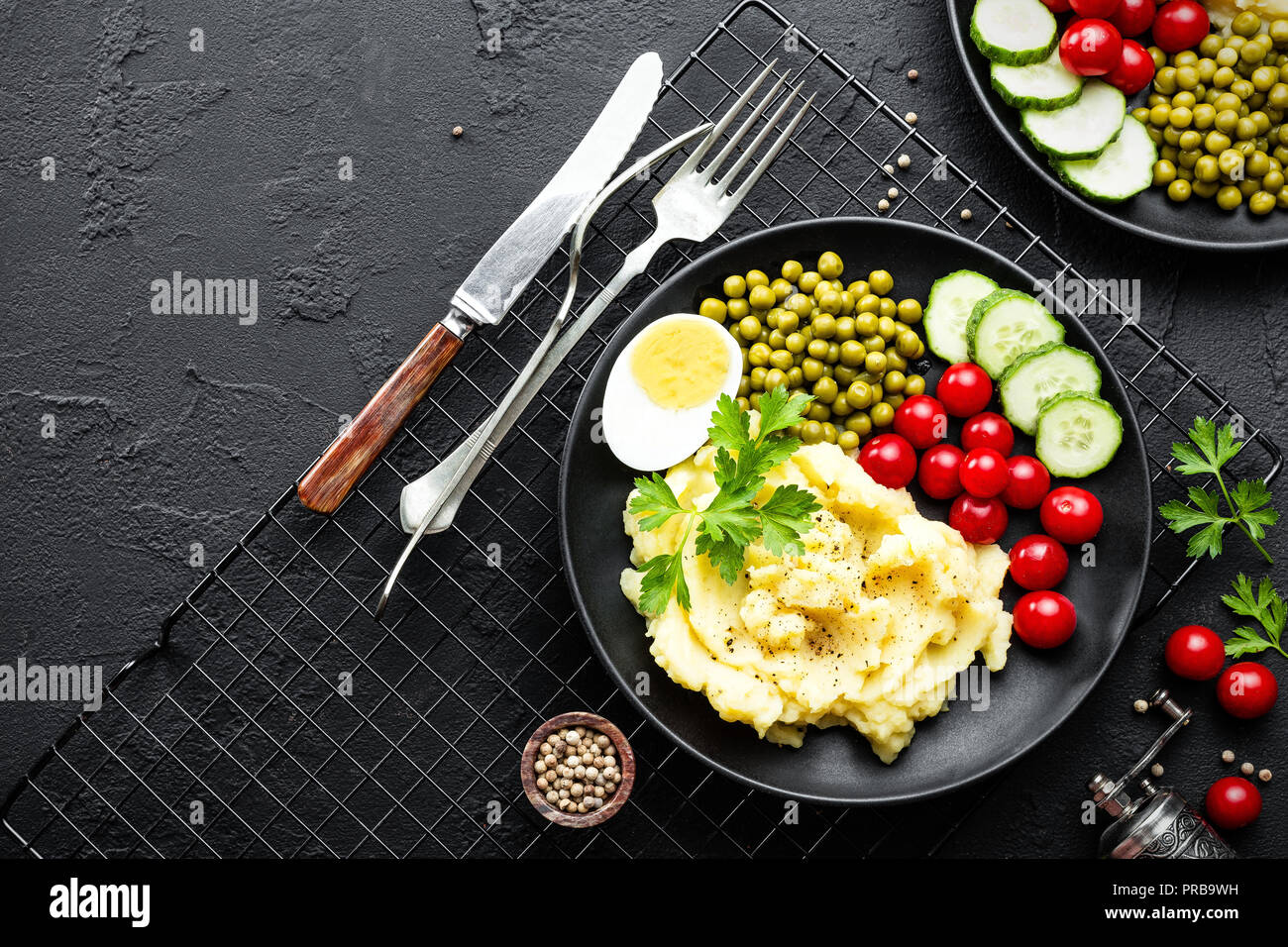 Mashed potato with green peas, tomatoes, cucumber and boiled egg. Potato puree on plate with vegetables and egg Stock Photo