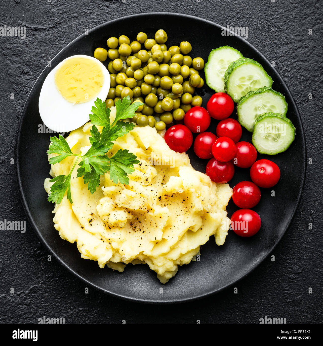 Mashed potato with green peas, tomatoes, cucumber and boiled egg. Potato puree on plate with vegetables and egg Stock Photo