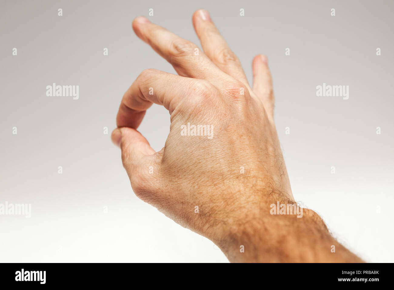 Closeup photo male hand showing Ok acceptance gesture over gray background Stock Photo
