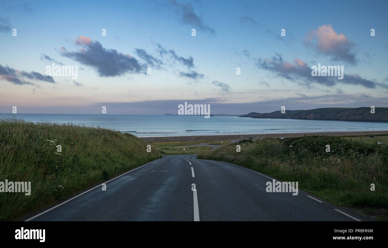 Empty asphalt road through the coast of Newgale at sunrise. Pembrokeshire in West Wales, UK Stock Photo