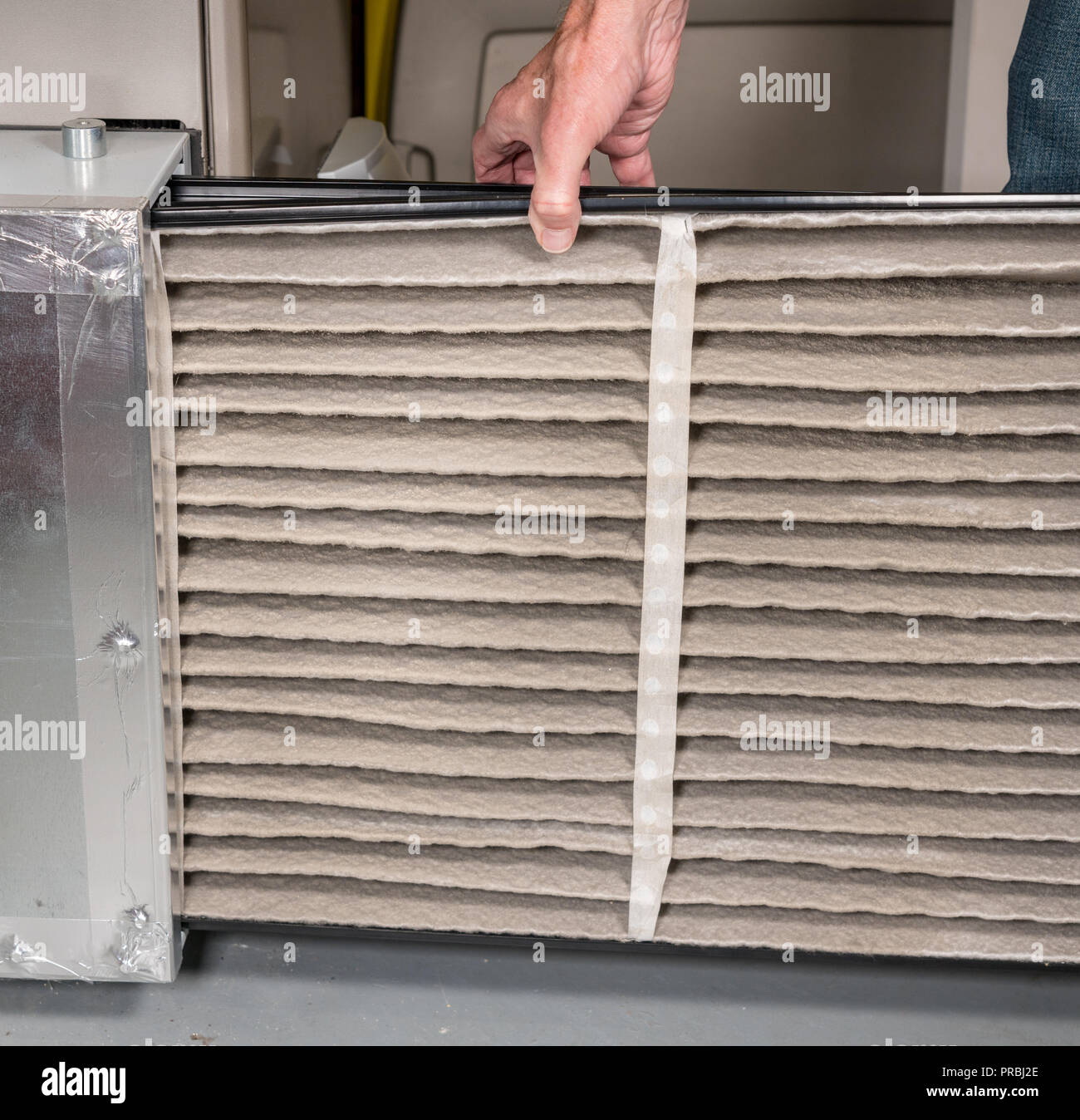 Senior man changing a dirty air filter in a HVAC Furnace
