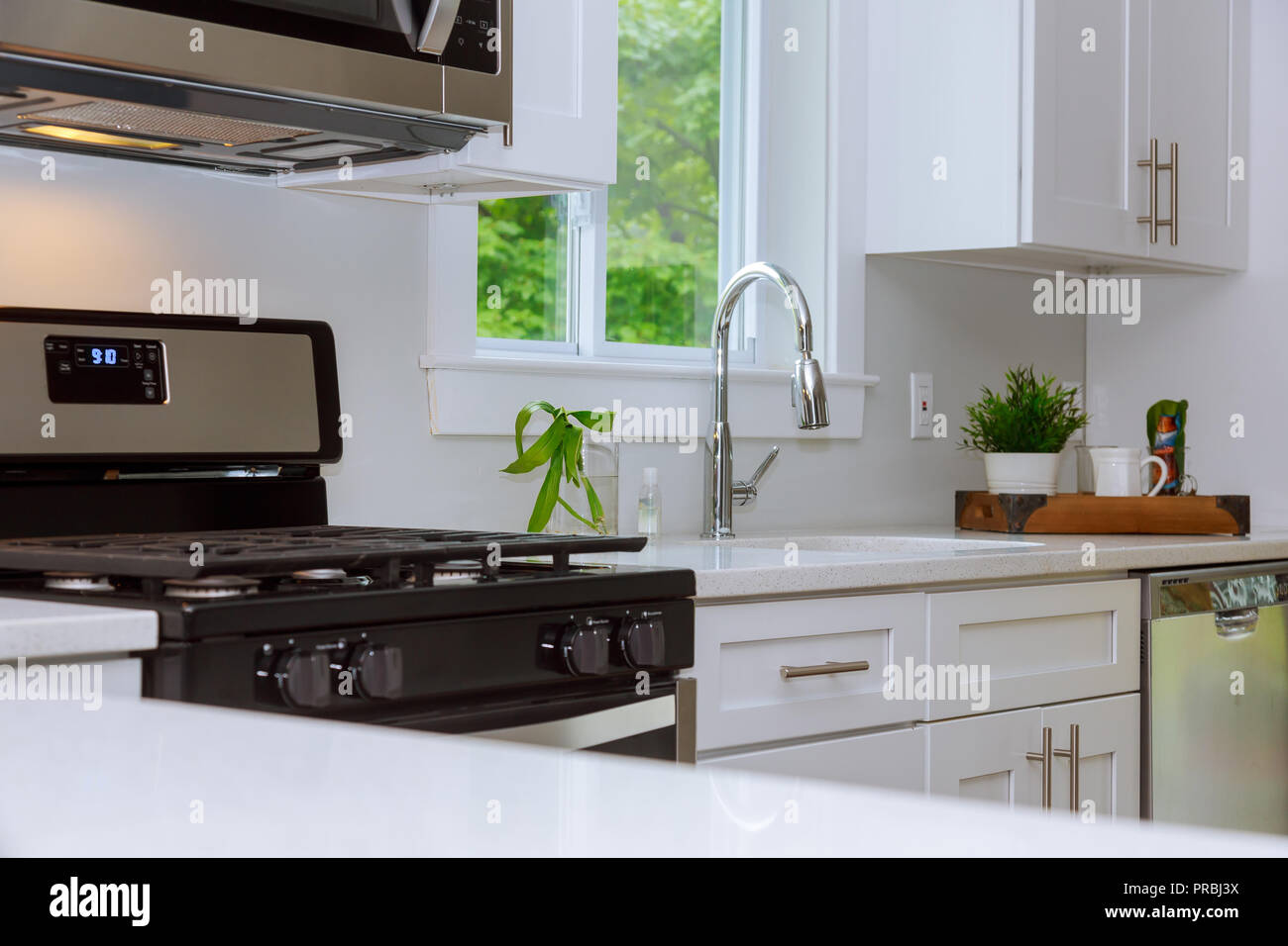 Interior of bright white kitchen in a stainless steel kitchen sink