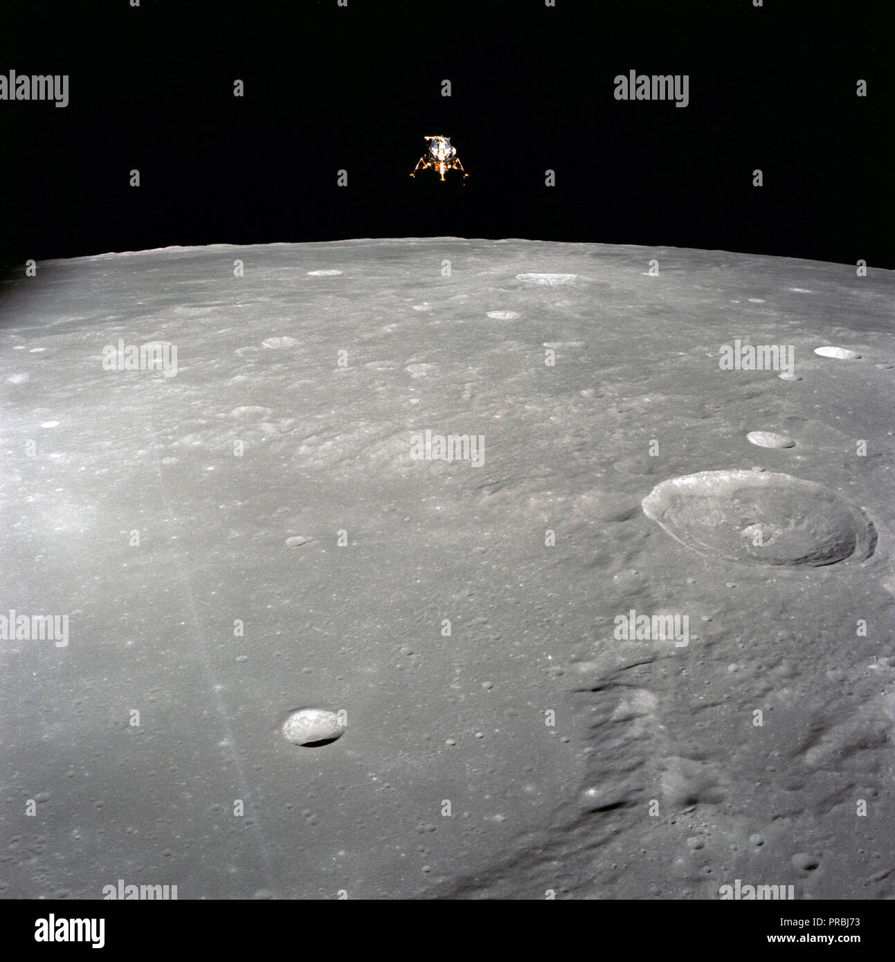 The Apollo 12 Lunar Module (LM), in a lunar landing configuration, is photographed in lunar orbit from the Command and Service Modules (CSM). The coordinates of the center of the lunar surface shown in picture are 4.5 degrees west longitude and 7 degrees south latitude. The largest crater in the foreground is Ptolemaeus; and the second largest is Herschel. Aboard the LM were astronauts Charles Conrad Jr., commander; and Alan L. Bean, lunar module pilot. Astronaut Richard R. Gordon Jr., command module pilot, remained with the CSM in lunar orbit while Conrad and Bean descended in the LM to explo Stock Photo